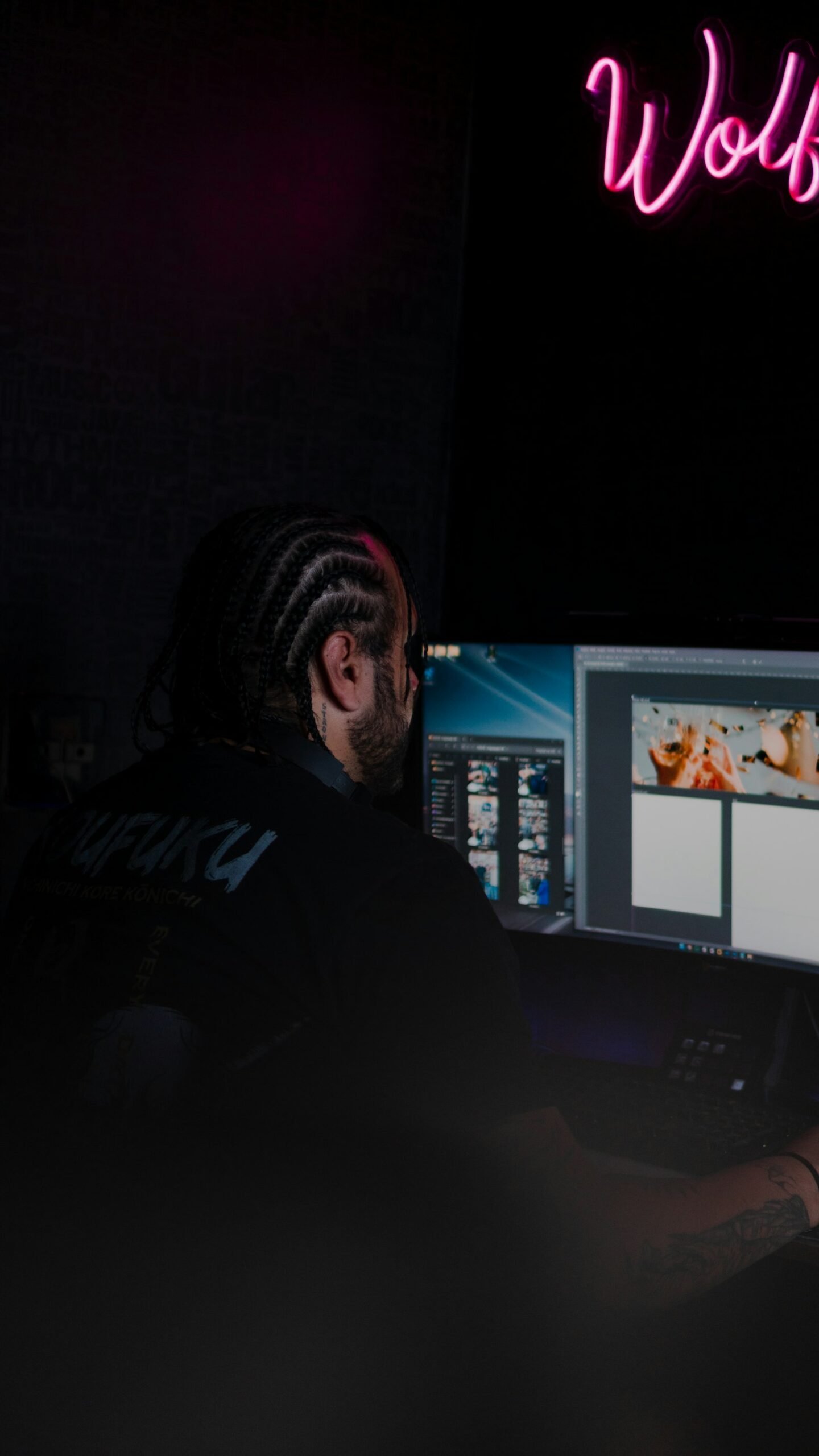 Man working on a computer with a neon sign in the background illustrating Content Repurposing: One Post, Five Platforms
