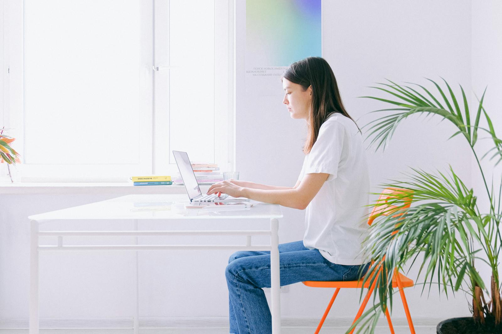Woman working on laptop at bright minimalist home office with plants