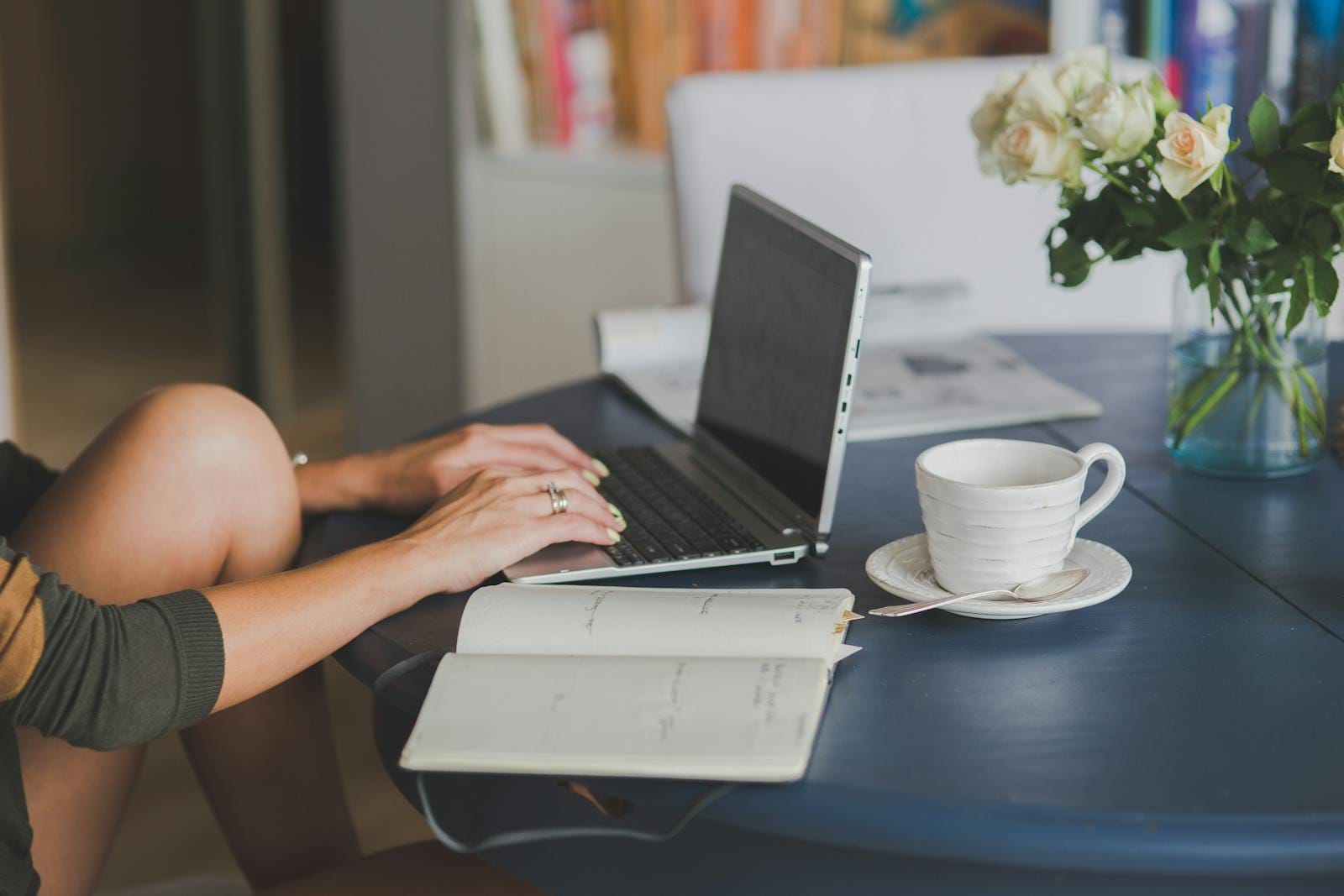 Female freelancer using laptop with coffee at home office desk