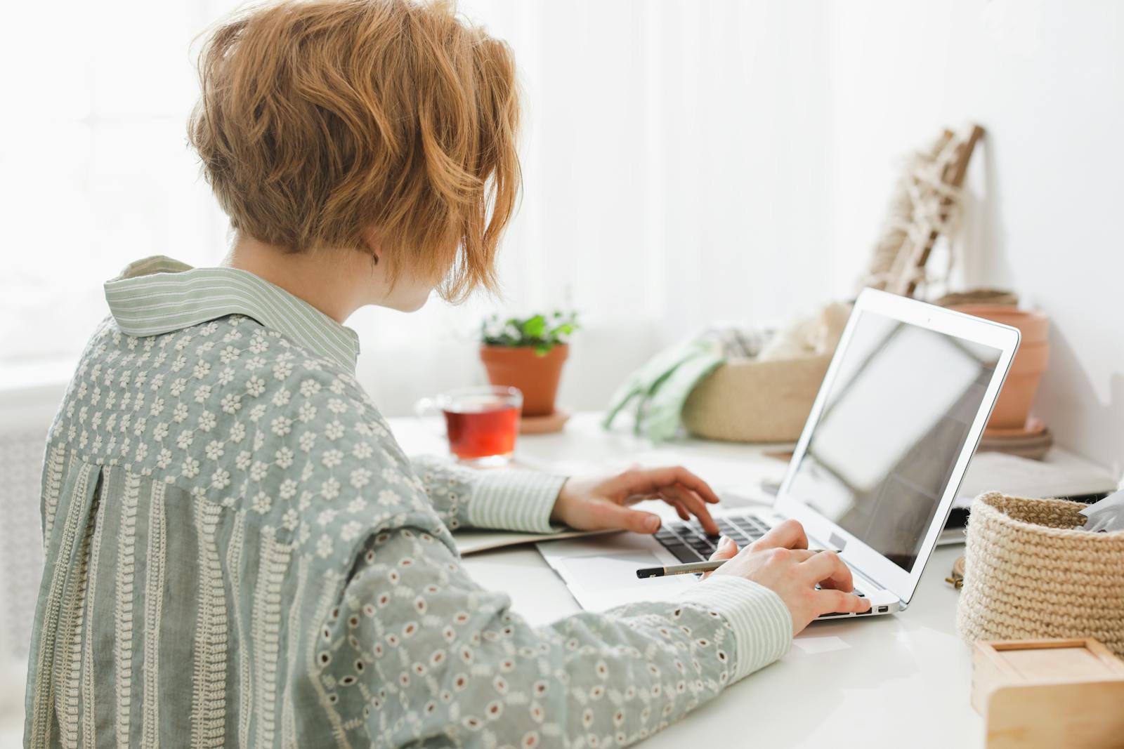 Woman working remotely in bright minimalist home office with laptop