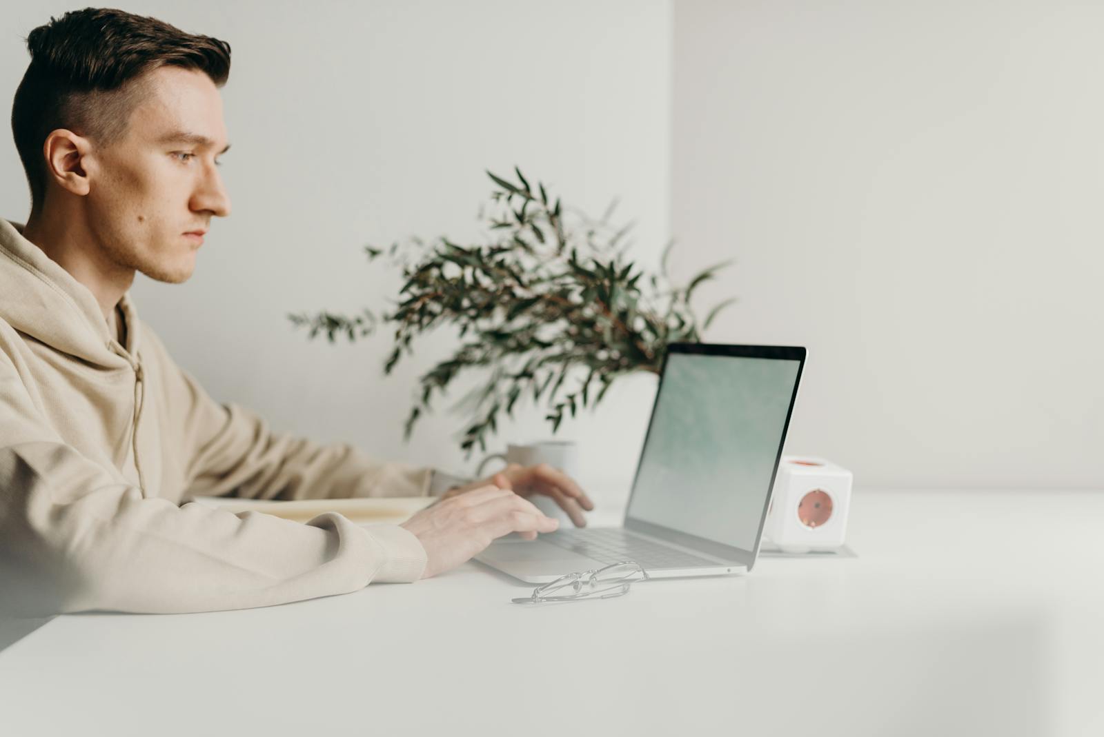 Young man focused on laptop in minimalist home office setting