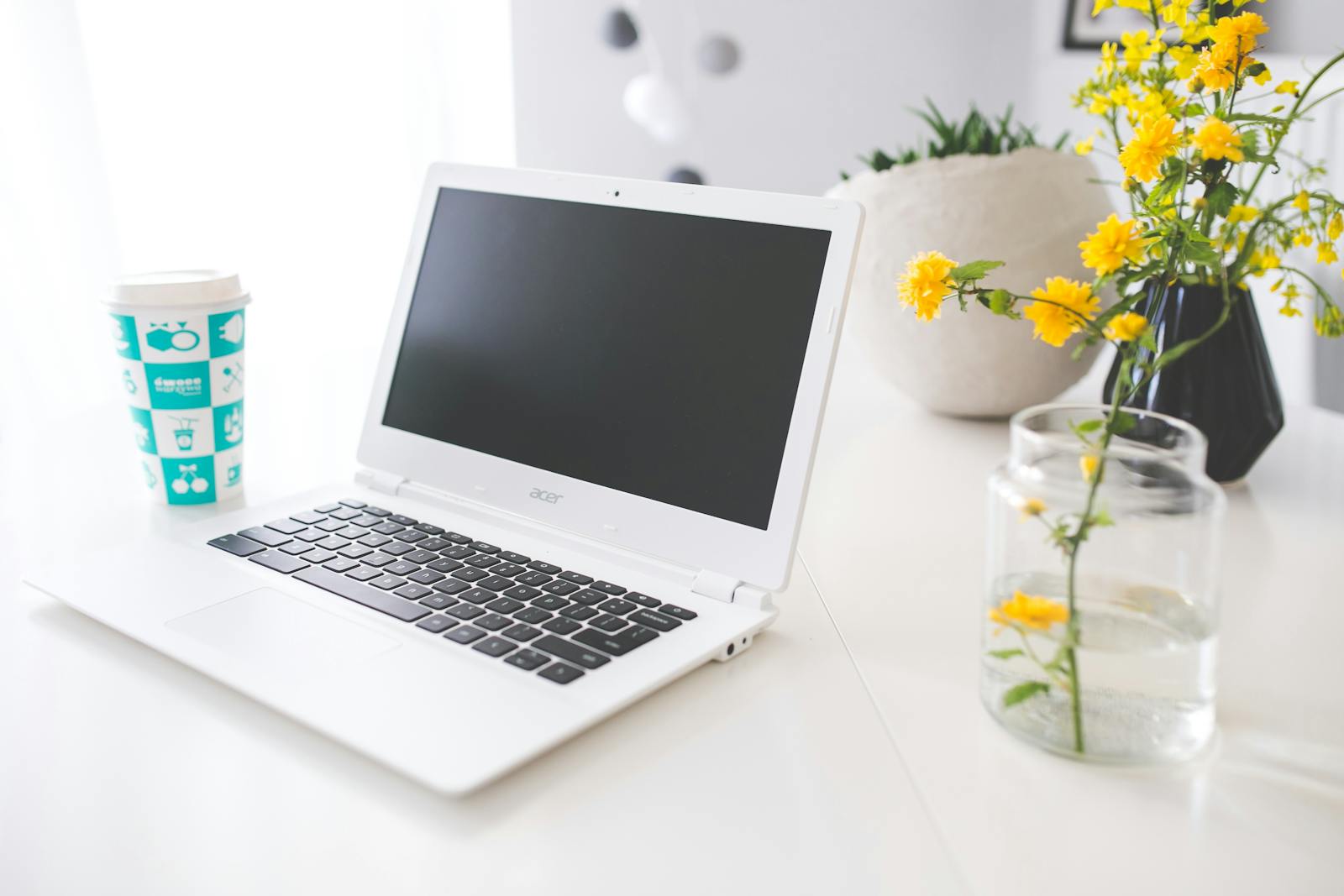 Bright workspace featuring laptop, coffee cup, and yellow flowers