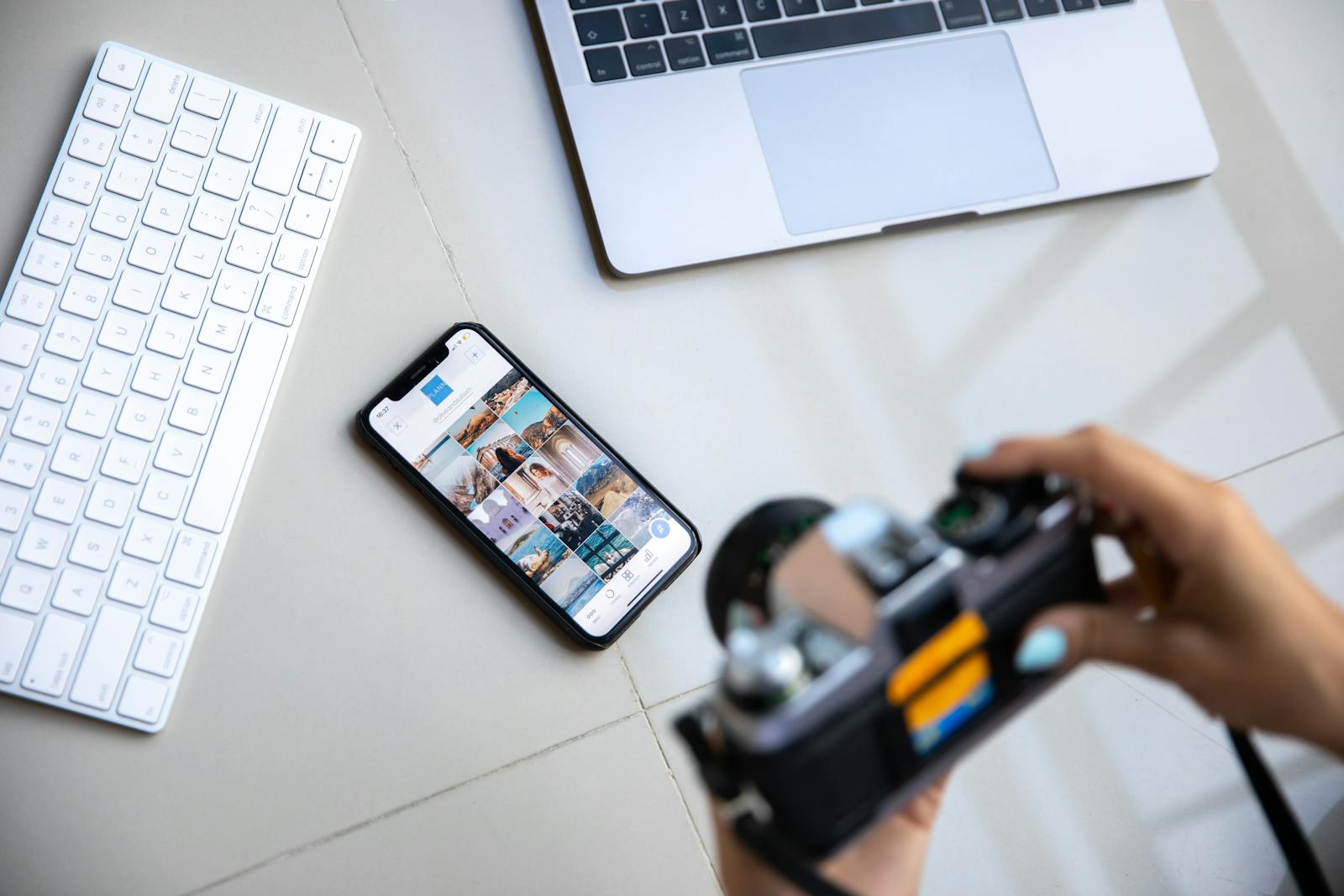 Person using vintage camera with smartphone and laptop in creative content setup