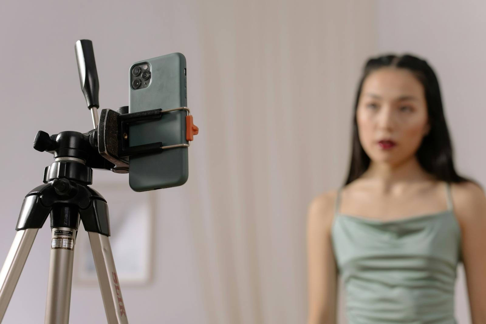Woman vlogging in front of smartphone tripod, engaged in content creation