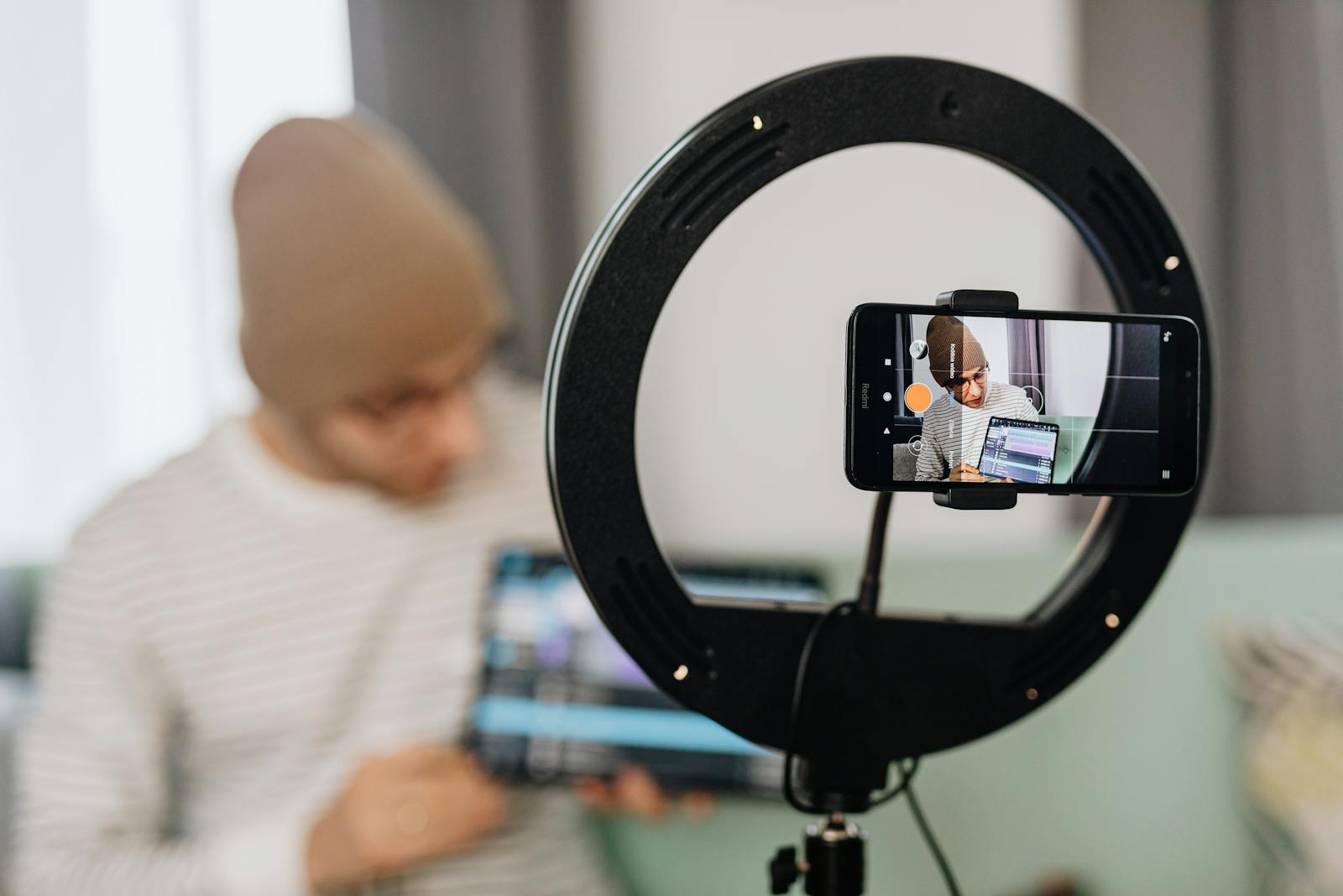 Vlogger creating content with smartphone and ring light, focused on creation