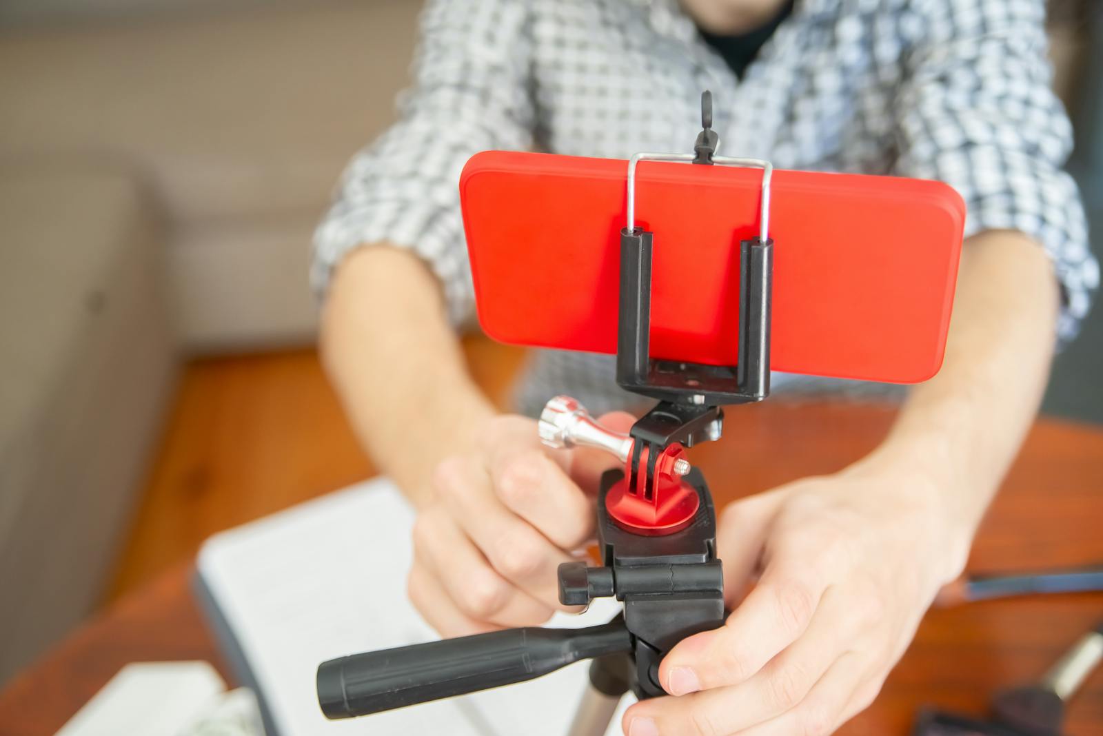 Person setting up smartphone on tripod, illustrating creator workflow