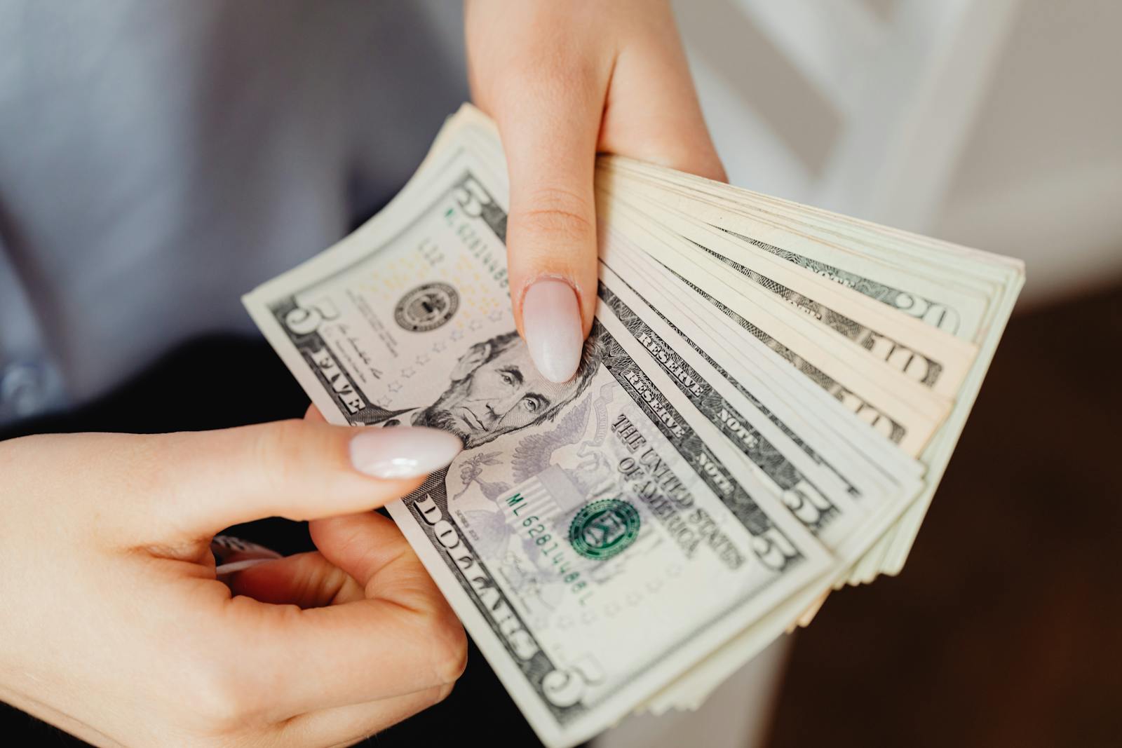 Hands counting US dollar bills, illustrating creator income