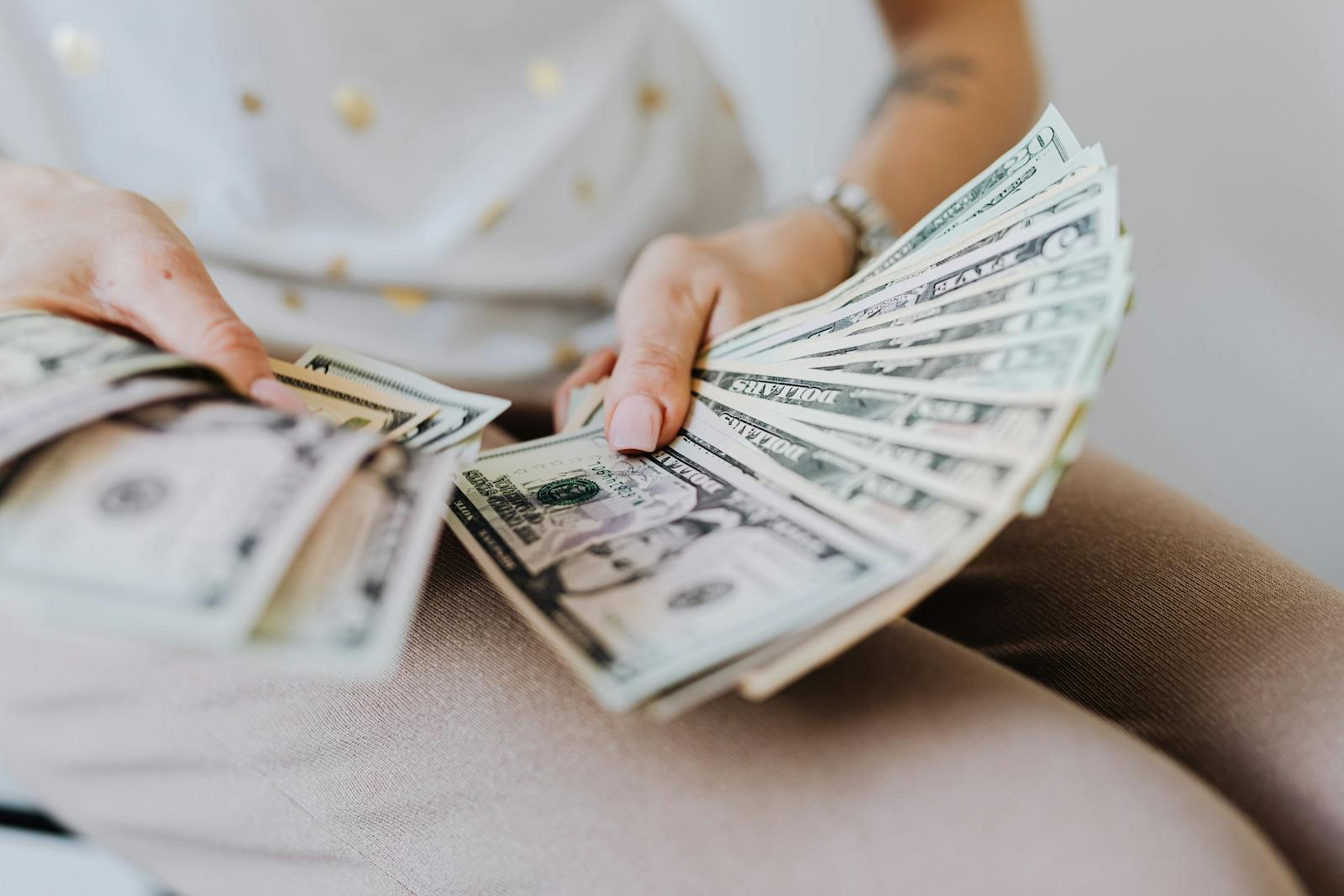 Close-up of hands holding and counting dollar bills, illustrating earnings