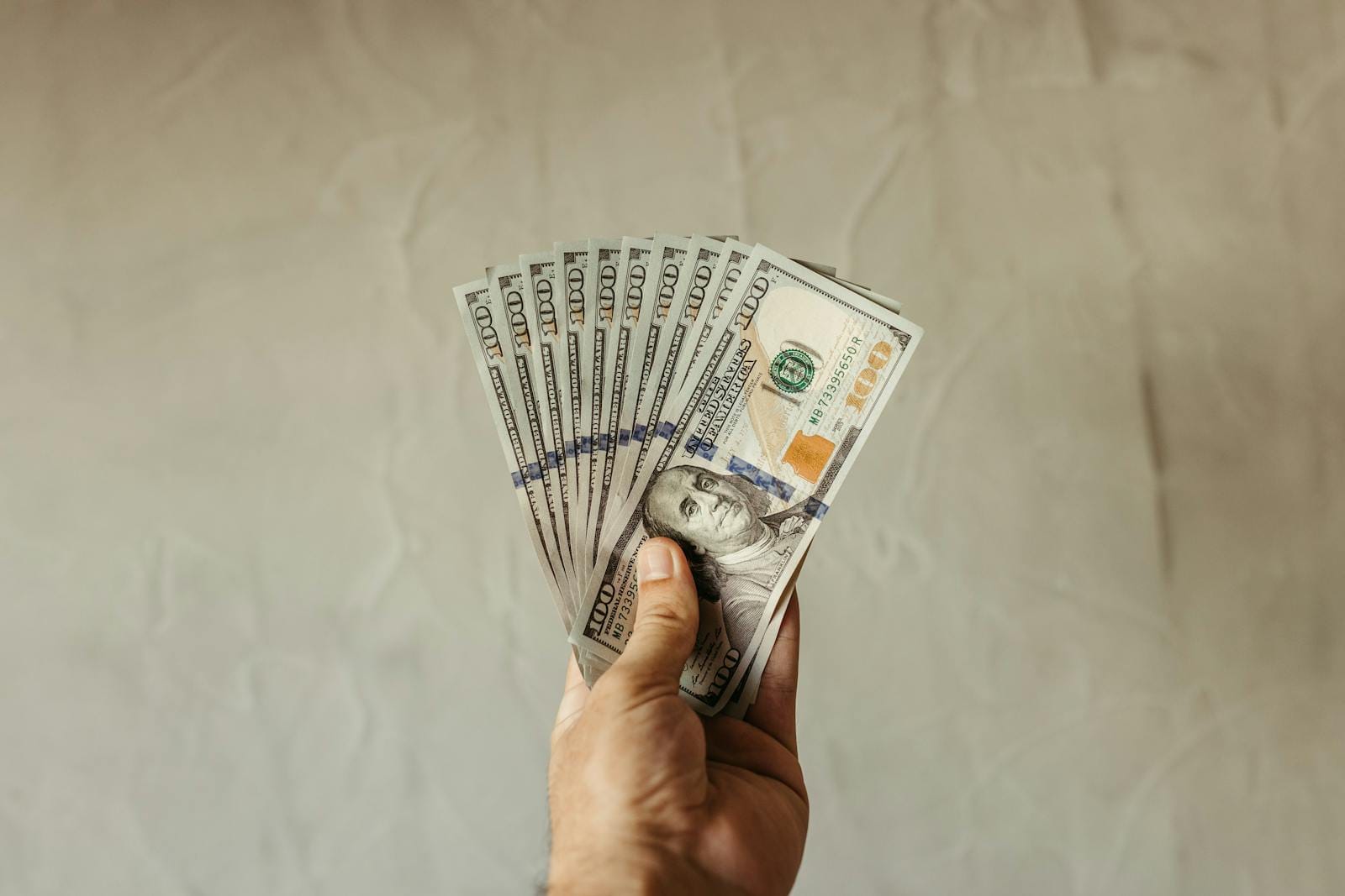 Hand holding multiple US dollar bills, illustrating wealth concept