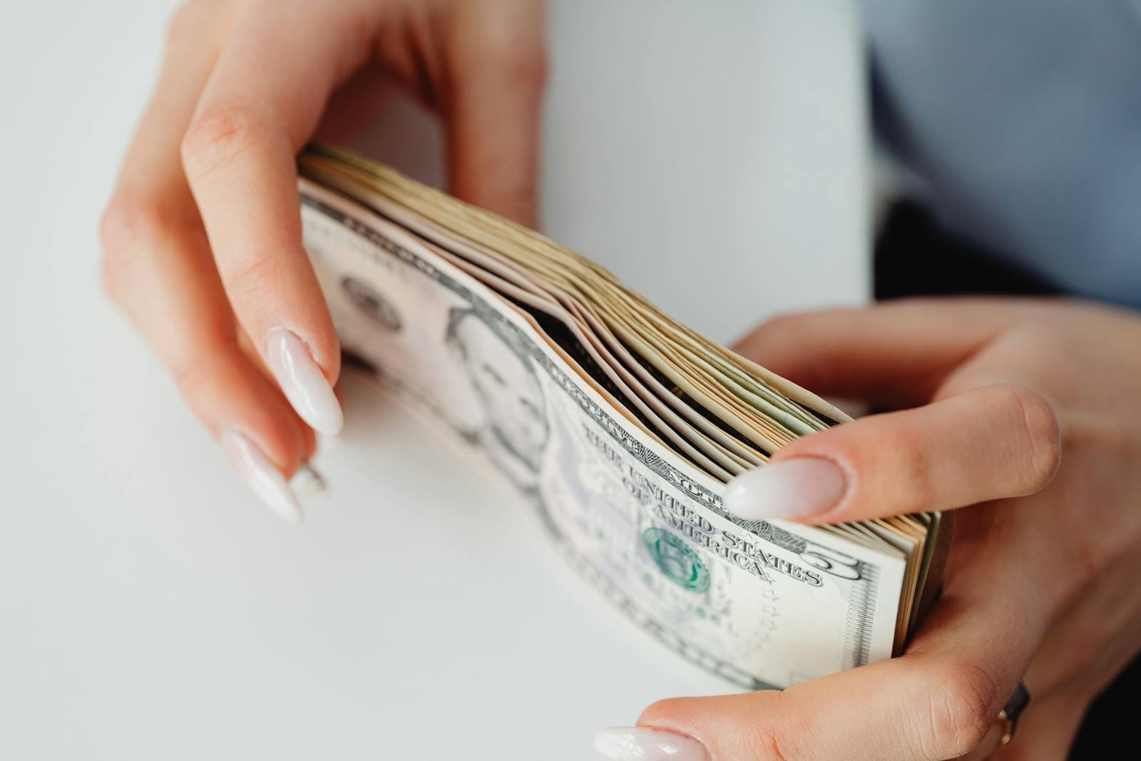 Hands holding stack of US dollar bills, illustrating finance and currency