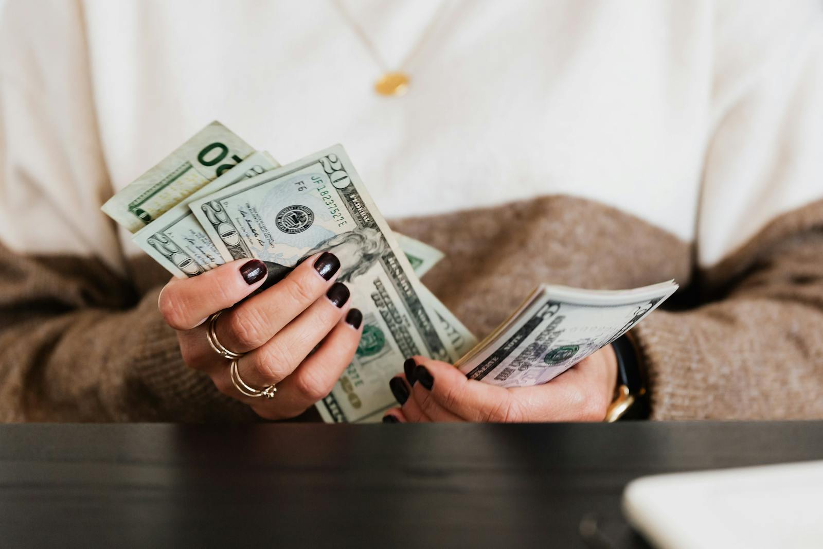Hands counting US dollar bills, illustrating money handling