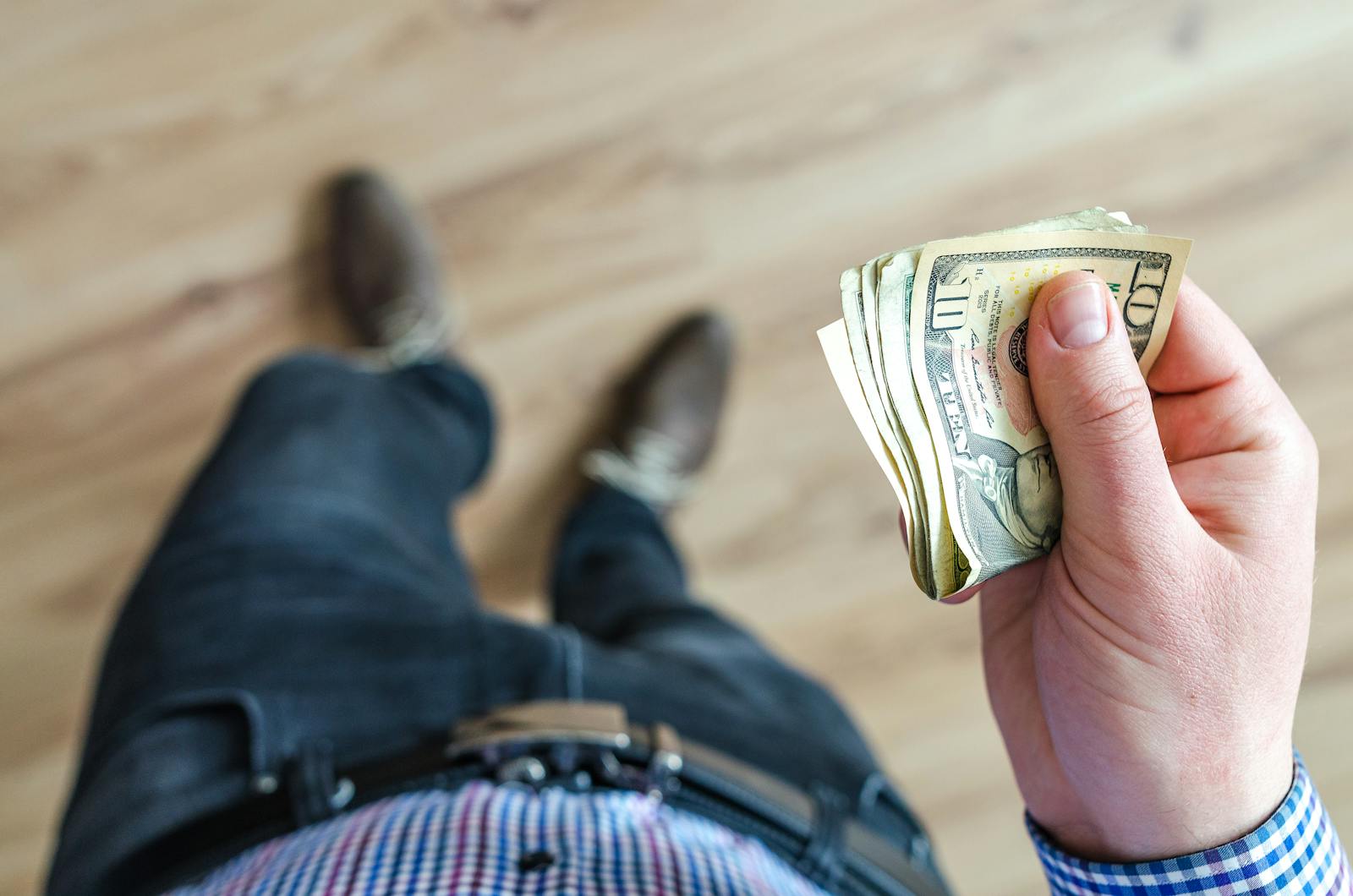 Man holding dollar bills indoors, illustrating personal finance