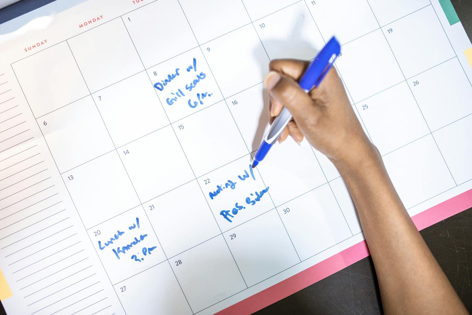 Person writing appointments on calendar, illustrating scheduling and planning