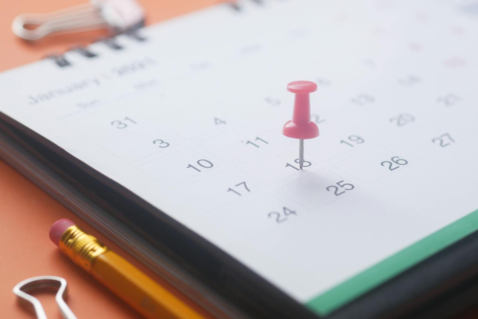 Calendar page with push pin and pencil, illustrating organization