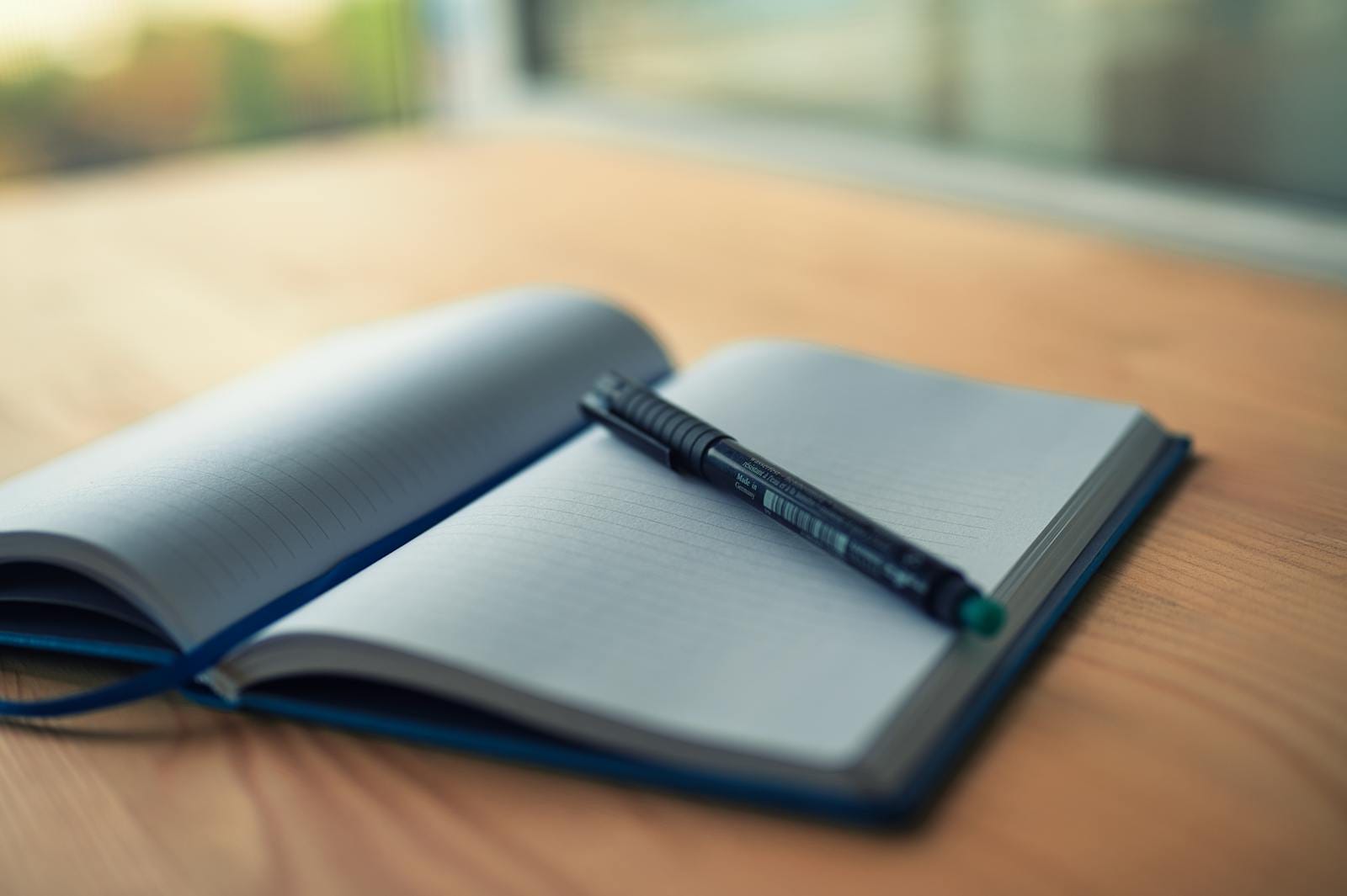 Open lined notebook with pen on wooden desk, illustrating creativity