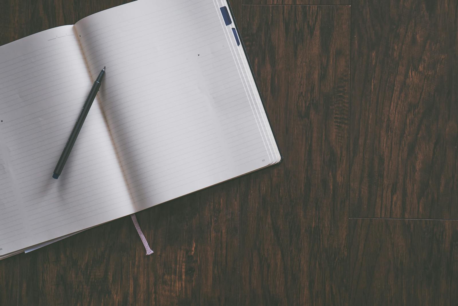 Open notebook with pen on wooden desk, illustrating productivity
