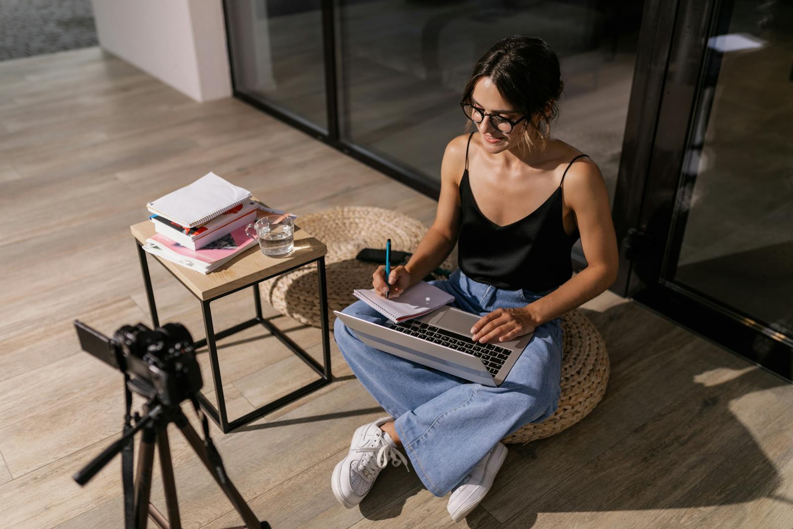 Young woman studying with laptop and camera, illustrating remote learning setup