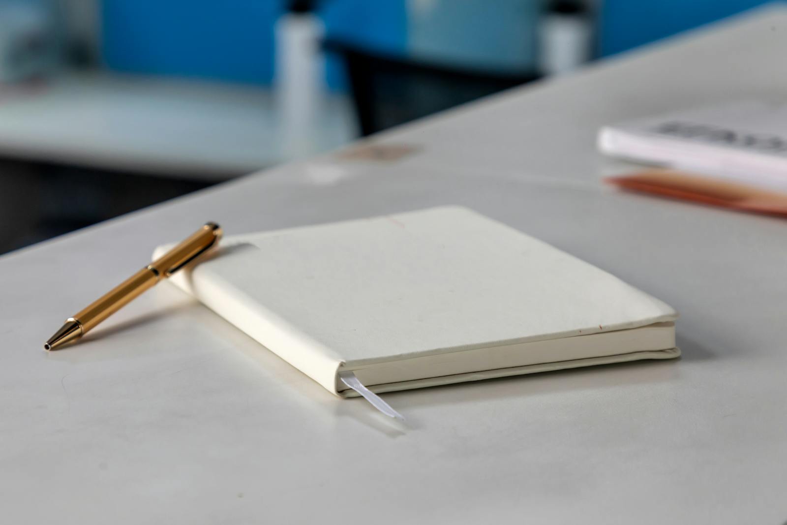 Minimalist white notebook and golden pen on modern desk