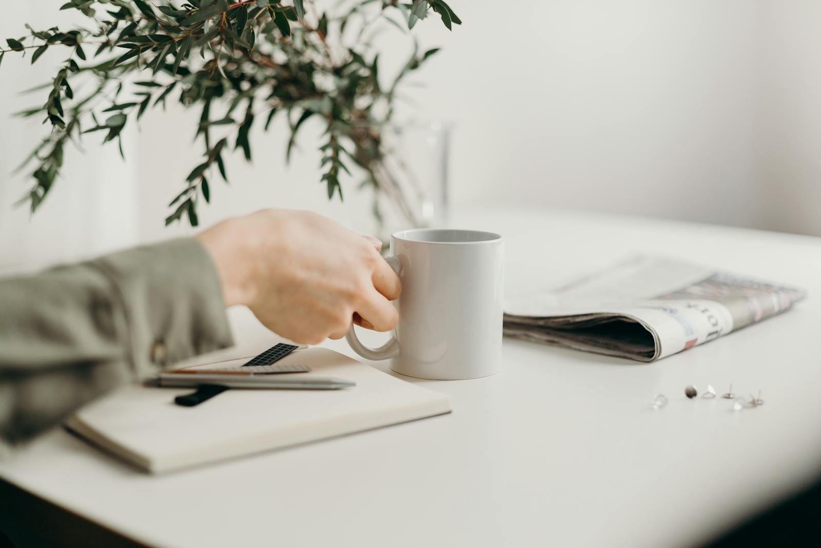 Minimalist workspace with mug, notebook, and greenery, illustrating productivity