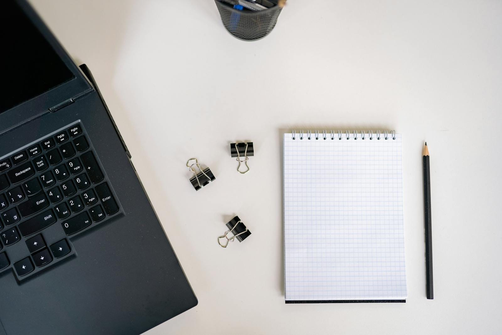 Top view office workspace with laptop, notepad, pencil, binder clips