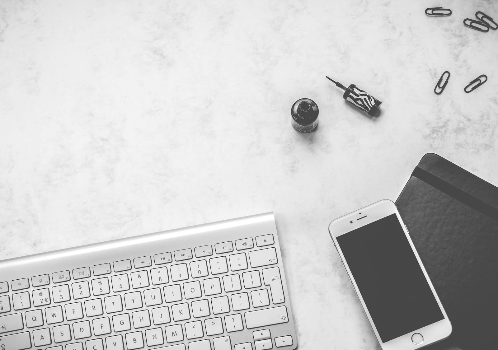 Black and white minimalist desk with keyboard, smartphone, stationery