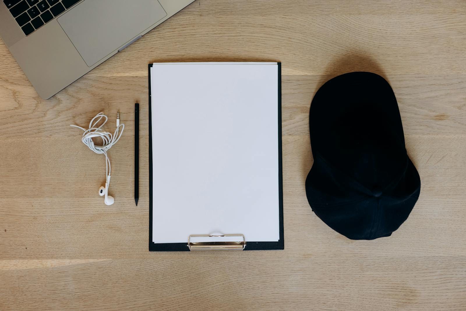 Flat lay of office essentials laptop, paper, pen on wooden surface