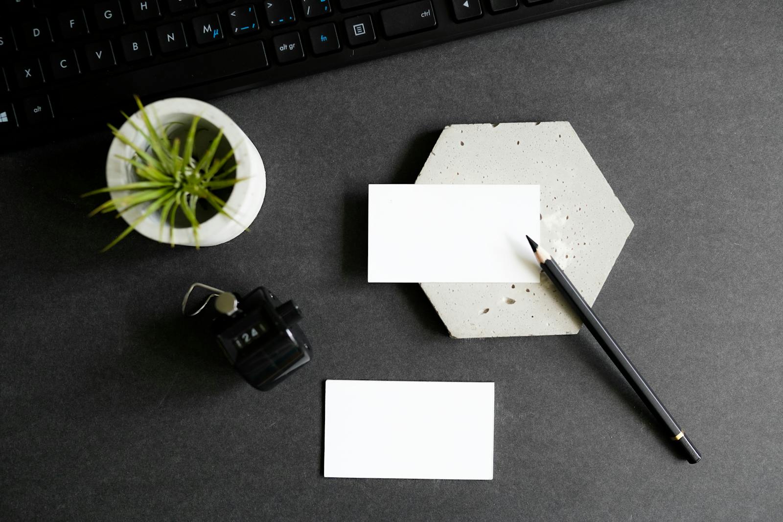 Top view stylish office desk with business cards, keyboard, houseplant