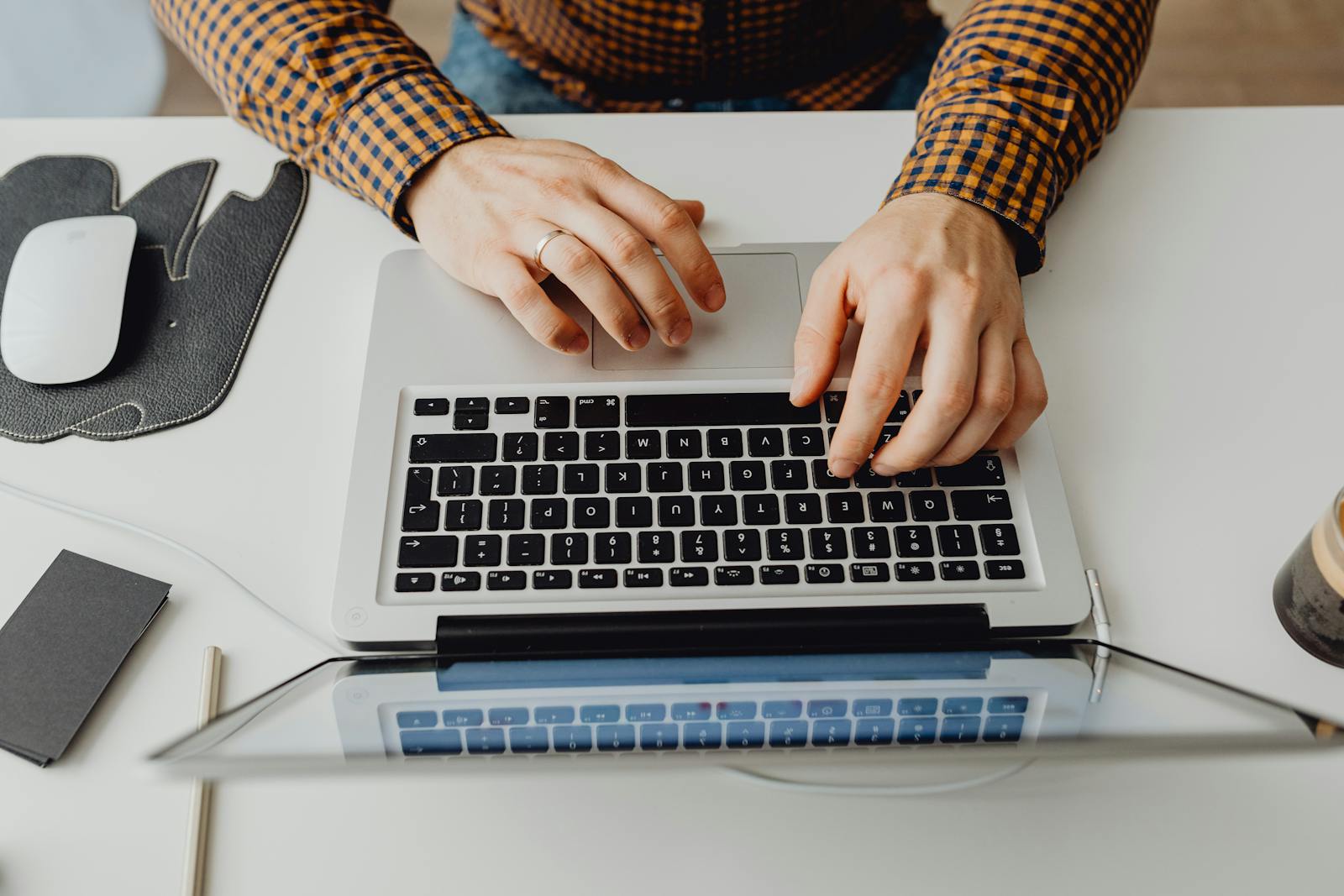 Hands typing on laptop keyboard in modern home office environment