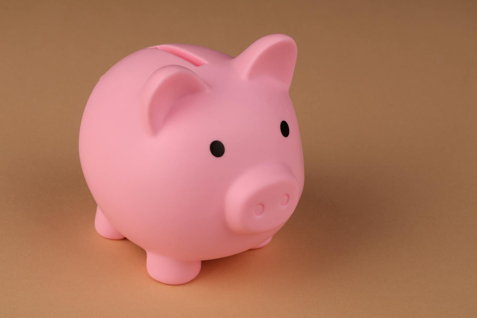 Pink piggy bank symbolizing savings and budgeting on brown backdrop