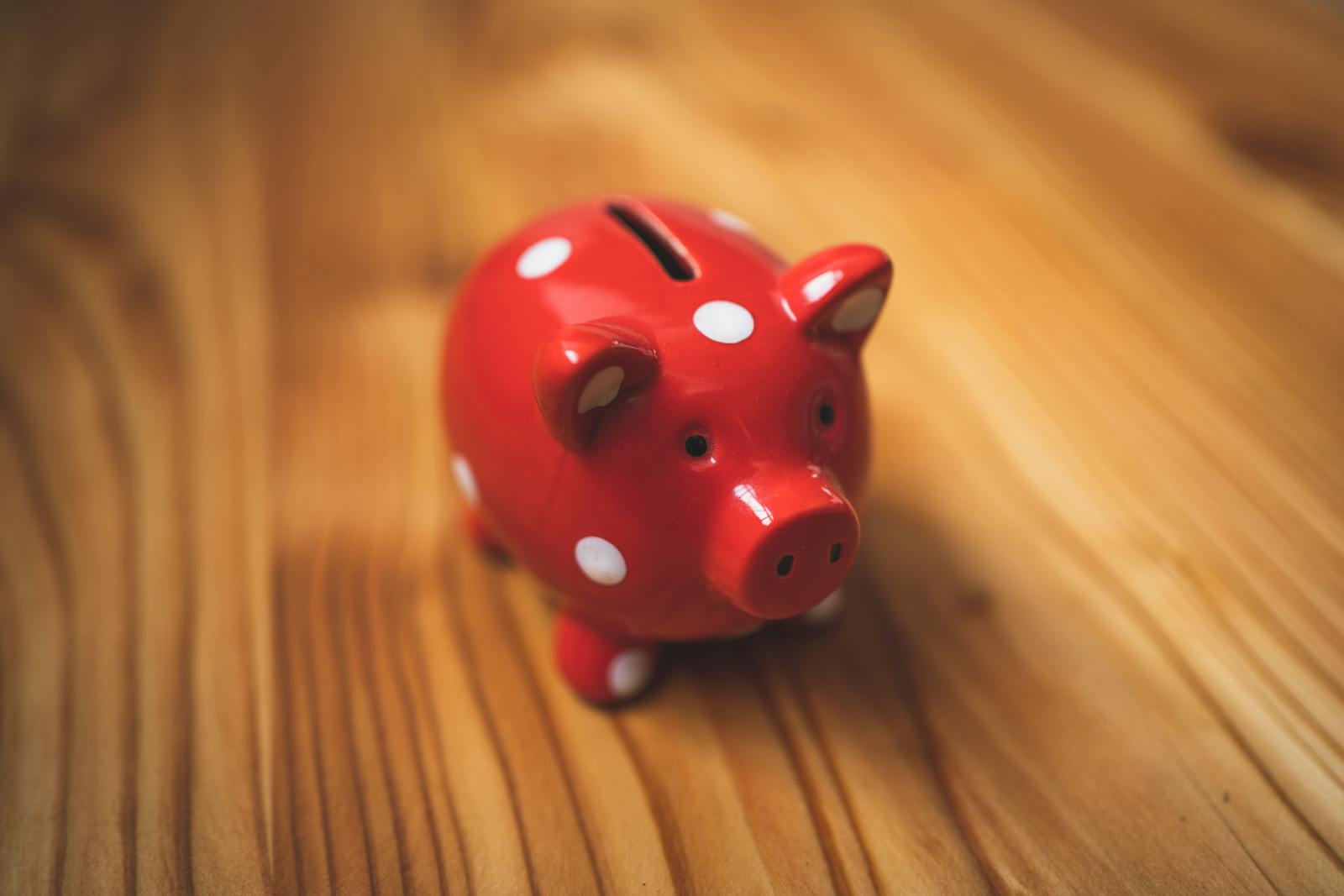 Red polka dot piggy bank on wooden surface, illustrating savings
