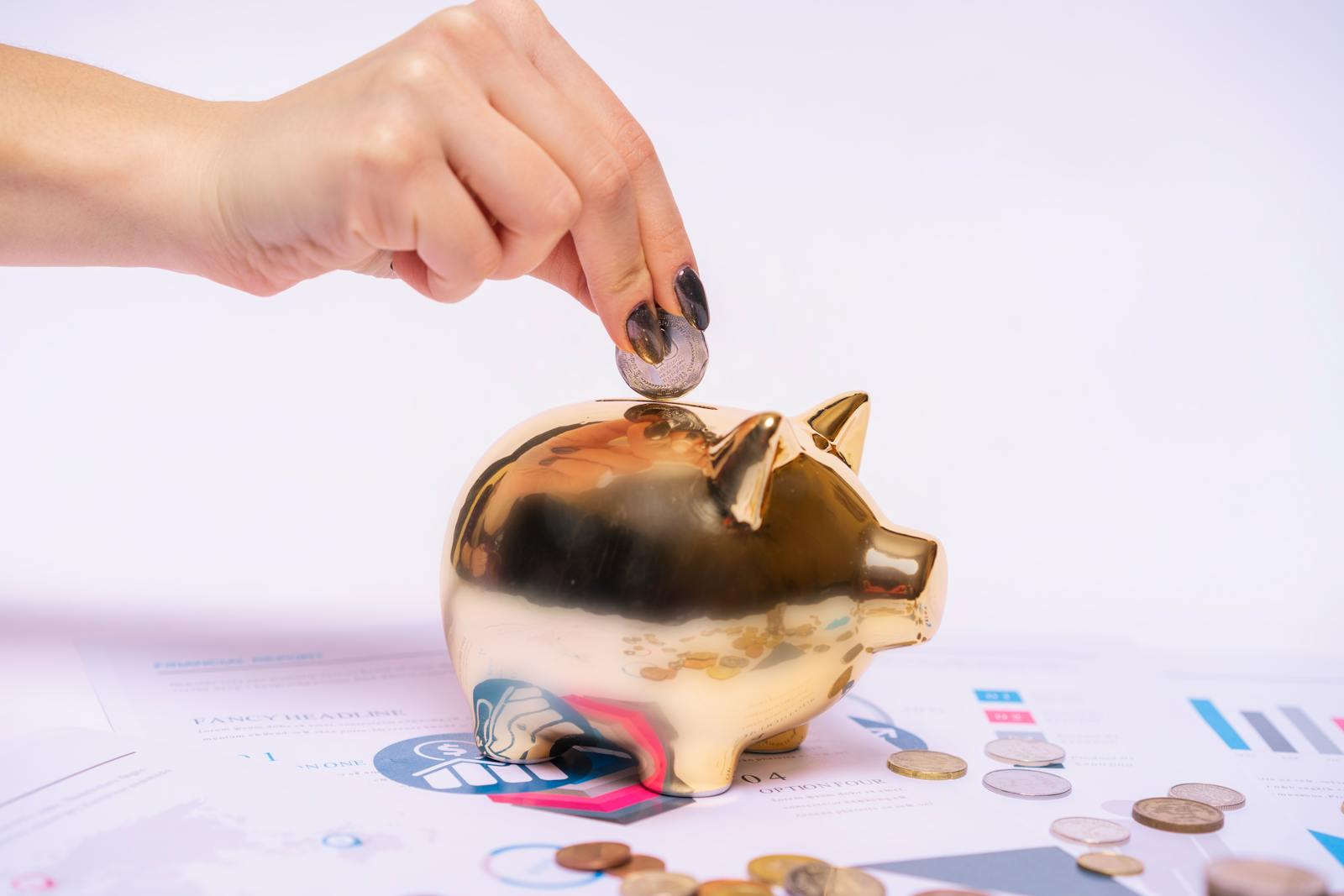 Hand placing coin into golden piggy bank with financial documents