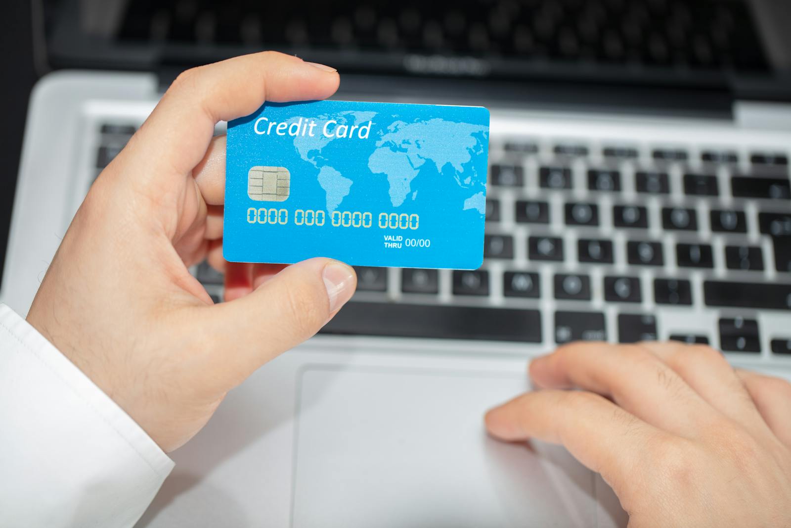 Person holding credit card near laptop for online shopping transaction