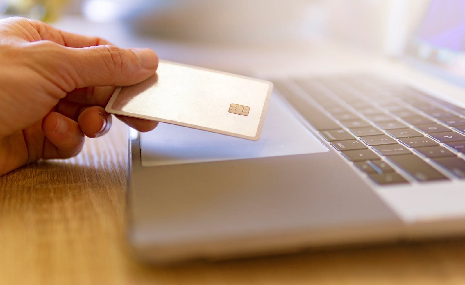 Person holds credit card near laptop, illustrating online shopping