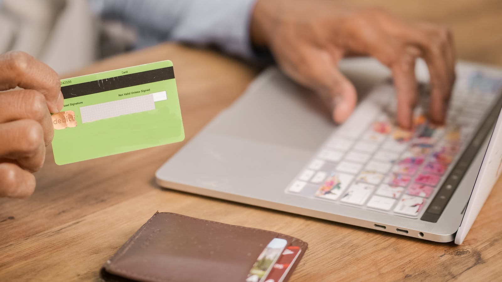 Person using credit card for online purchase on laptop at wooden table