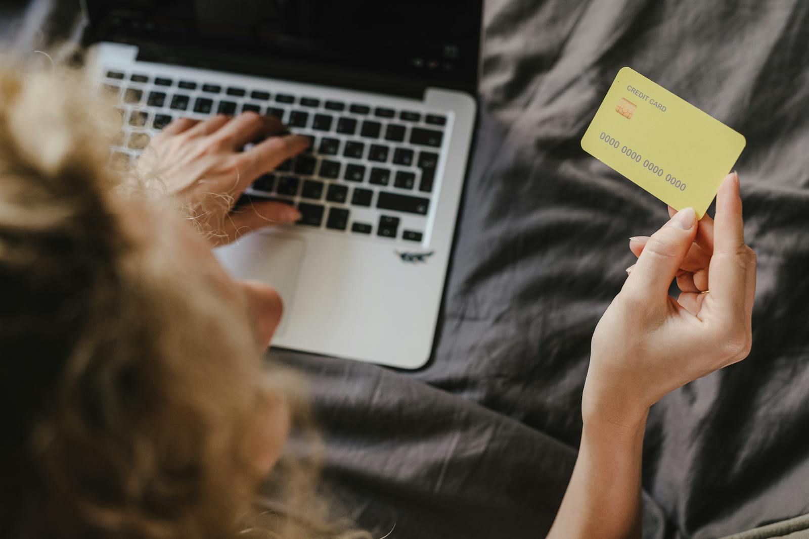 Person using credit card for online shopping captured from above