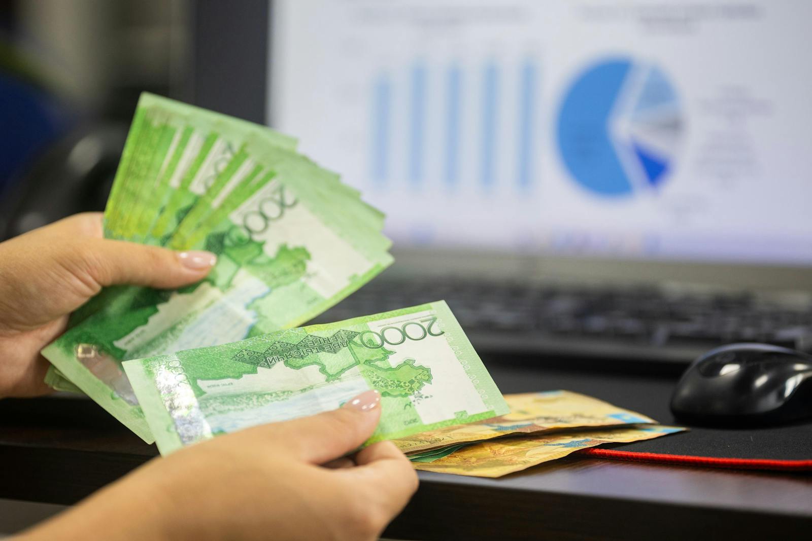 Hands counting cash with financial charts in background, illustrating time-allocation results
