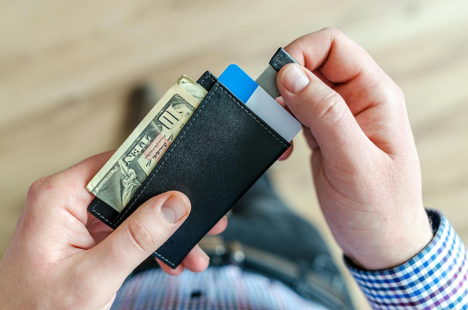 Hands pulling credit card from wallet with cash visible, illustrating Self credit builder review