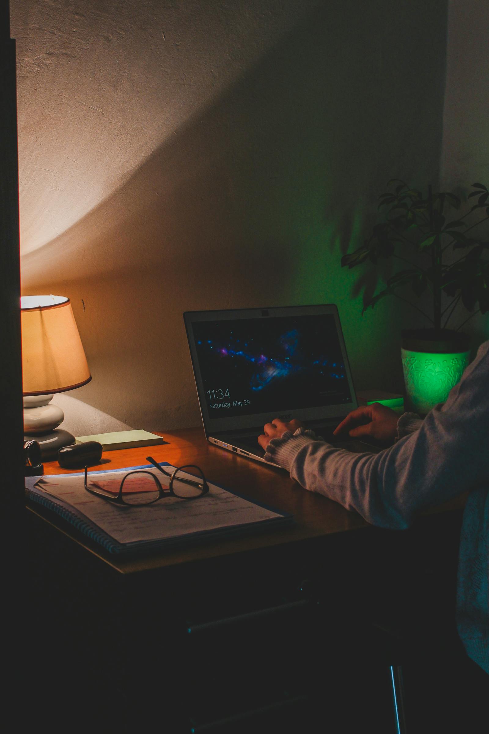 Person working laptop dimly lit home office