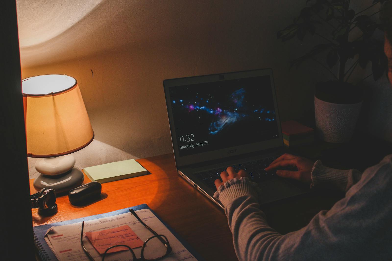 Warm ambient lighting in workspace with laptop and table lamp creating cozy atmosphere