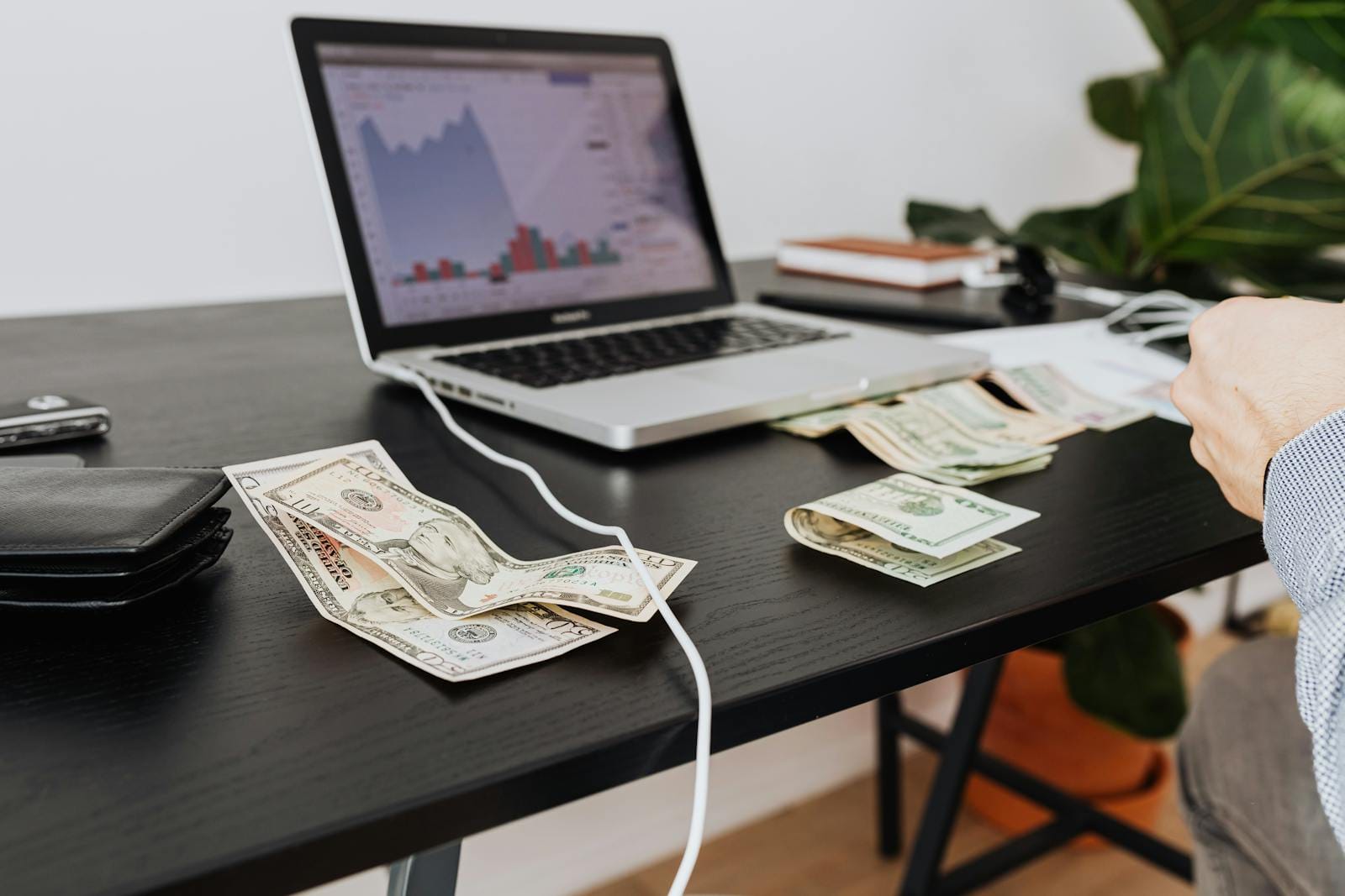 Workspace with cash, laptop, and financial graph showing investment analysis