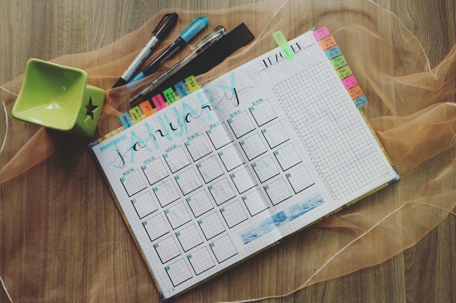 January planner with pens and green cup, ideal for organizing tasks