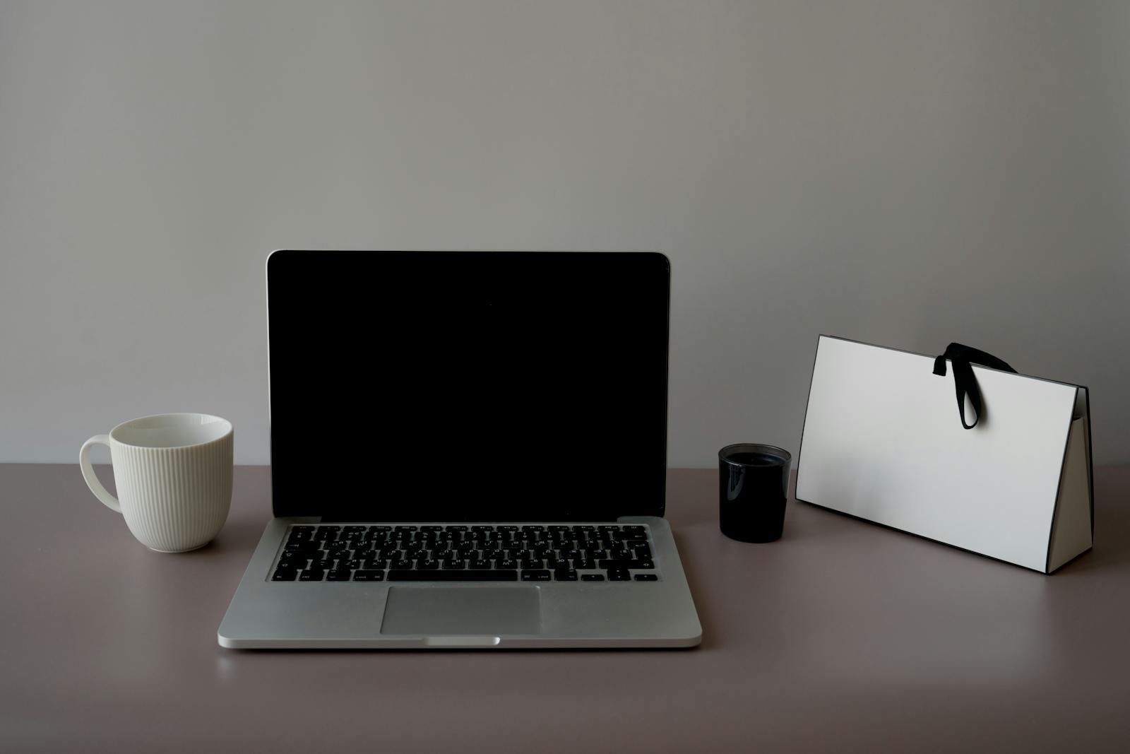 Sleek minimalist workspace with laptop, ceramic cup, and stylish paper bag